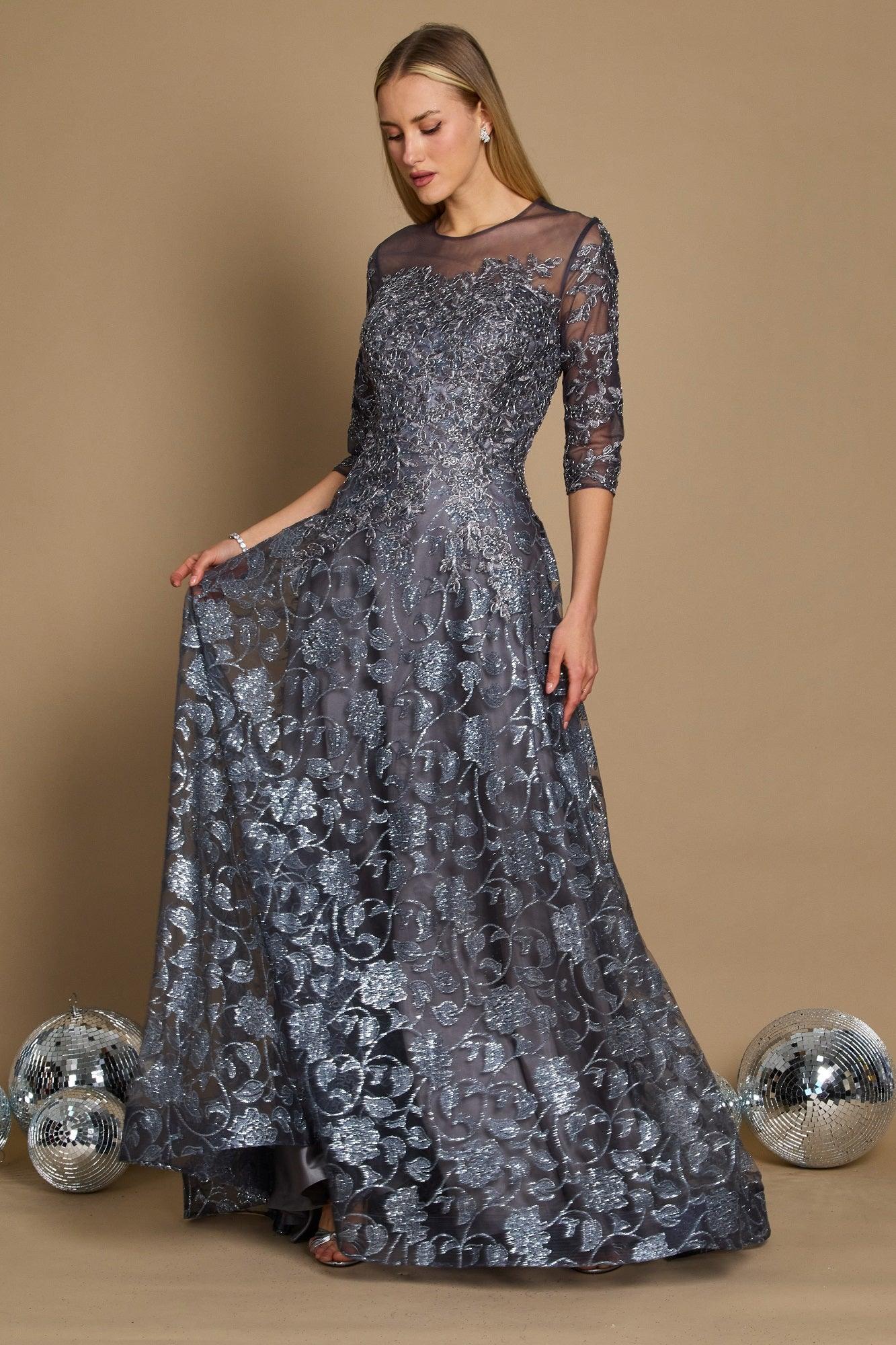 A long formal evening dress in charcoal gray, featuring intricate lace detailing and a flowing silhouette, elegantly draping to the floor.